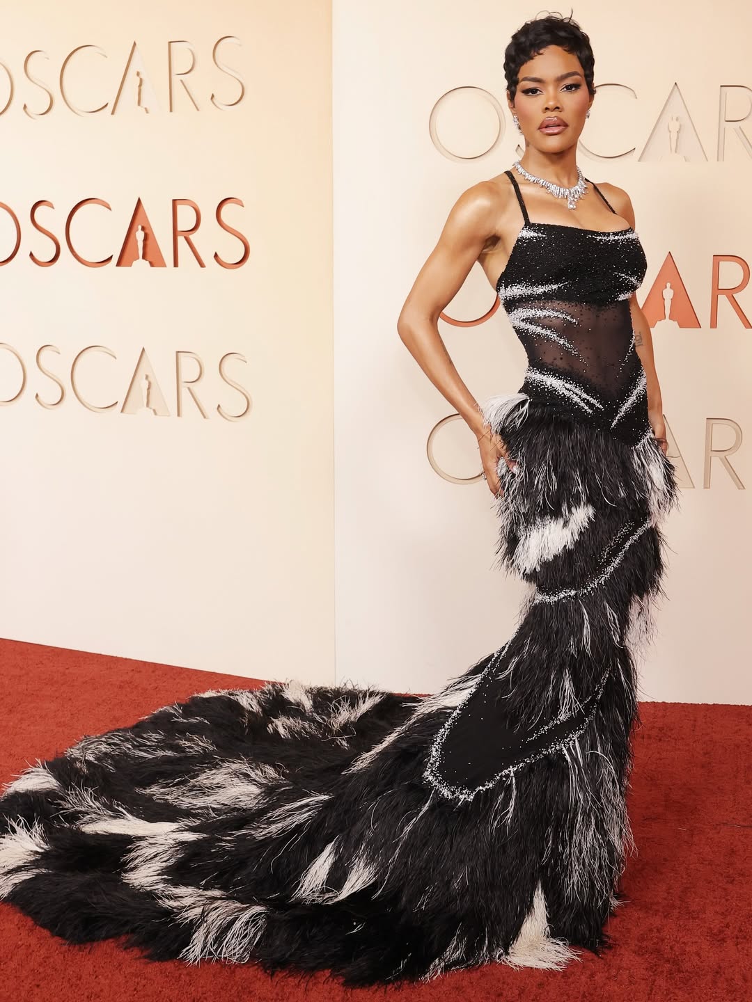 Teyana Taylor in a black and white chiffon Chanel gown with feathered train on the Oscars 2026 red carpet.