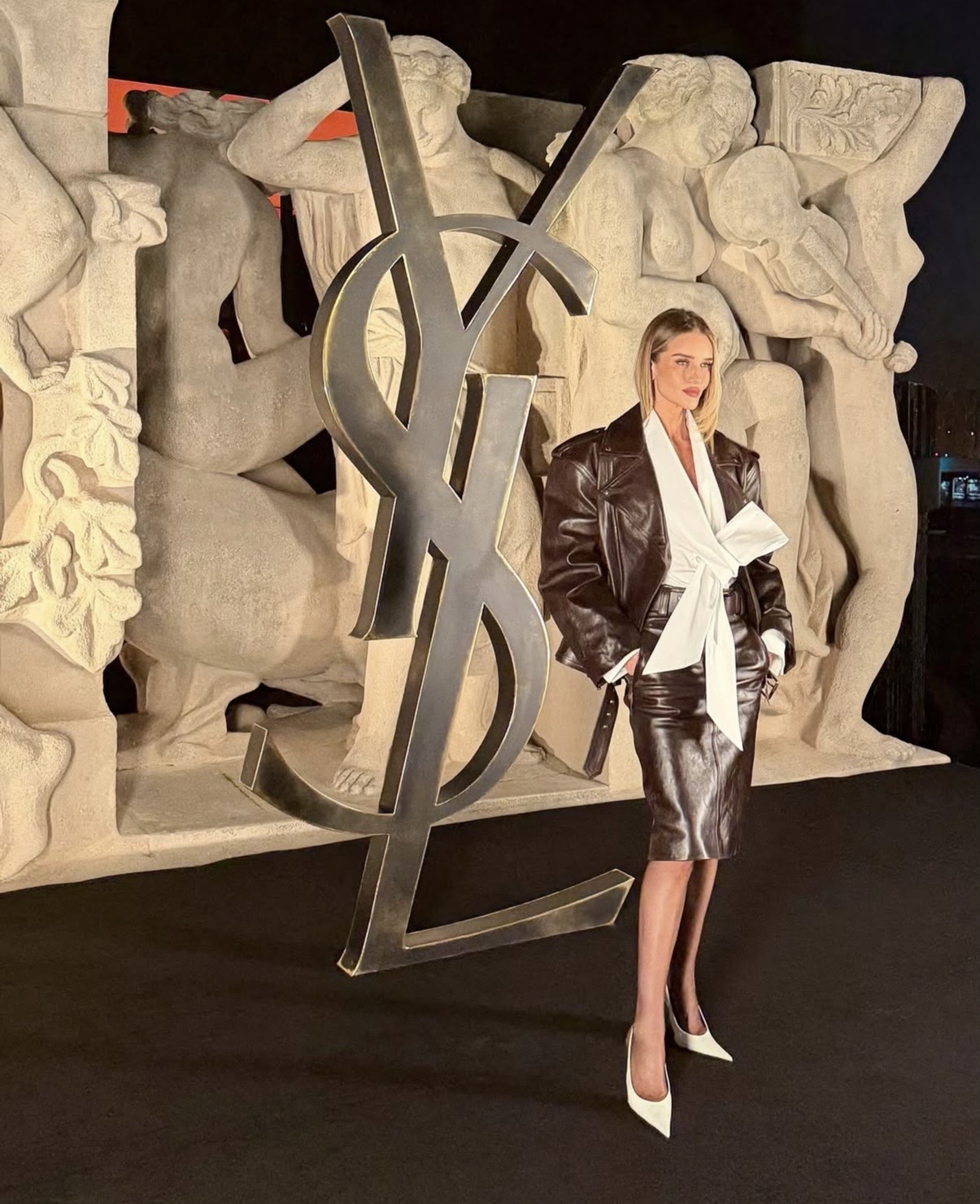 Rosie Huntington-Whiteley in a brown leather Saint Laurent jacket and pencil skirt paired with a white bow blouse at the Paris Fashion Week show — Paris Fashion Week celebrity styles