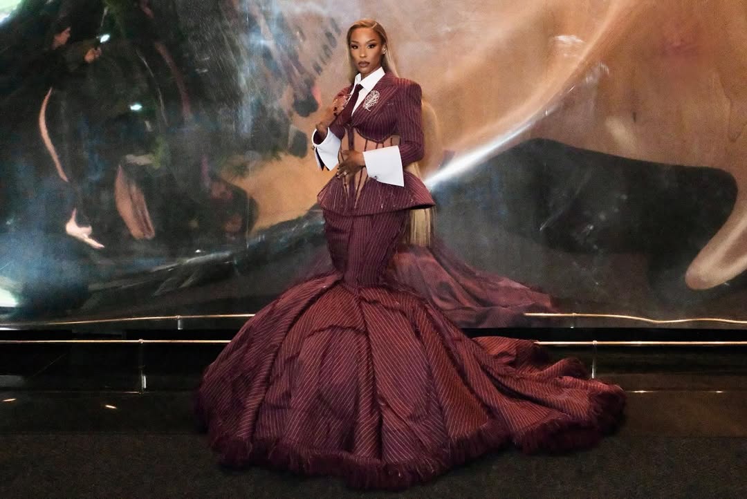 Savannah James in a custom Hanifa burgundy pinstripe suit gown with a mesh corset and mermaid skirt at the 2025 Met Gala in New York City.