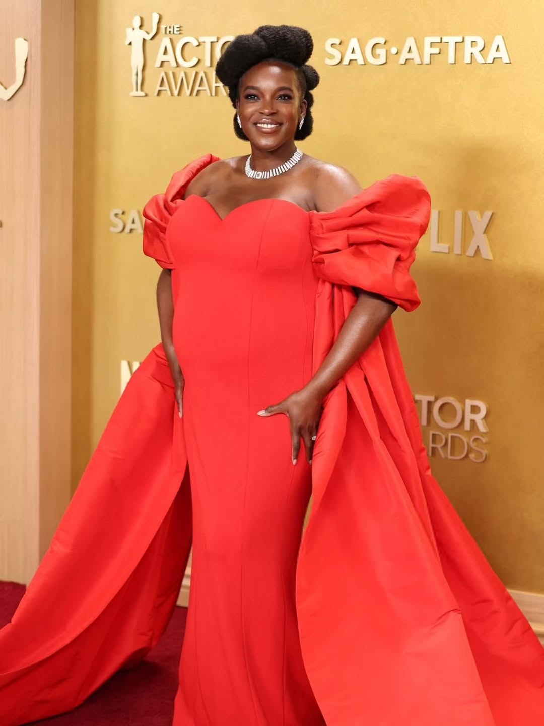 Wunmi Mosaku at the 32nd Actor Awards in a custom red Louis Vuitton gown with exaggerated off-the-shoulder sleeves and a train