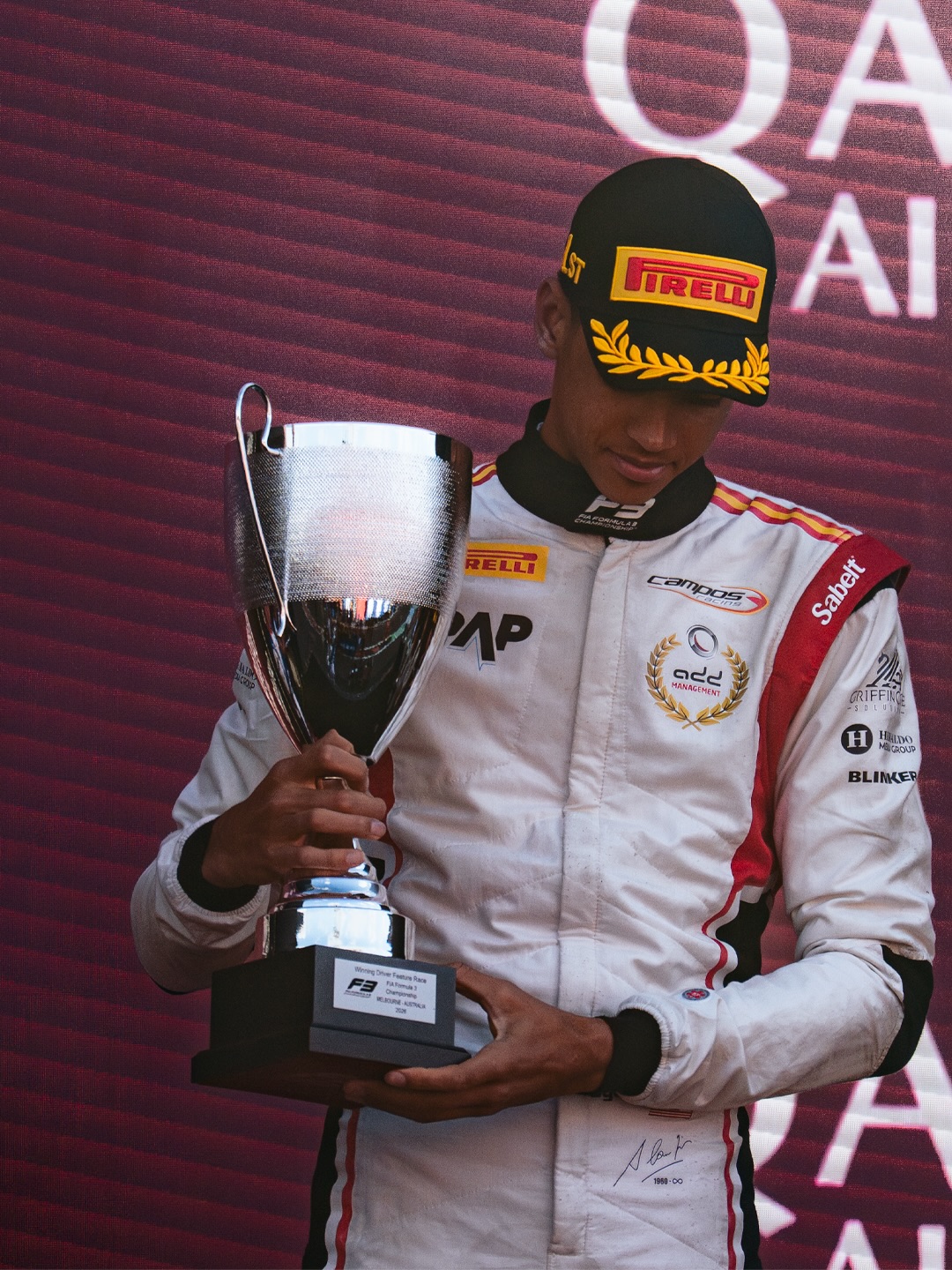 Close-up of Ugo Ugochukwu in his Campos Racing suit holding the winner's trophy on the podium at the 2026 Australian Grand Prix.