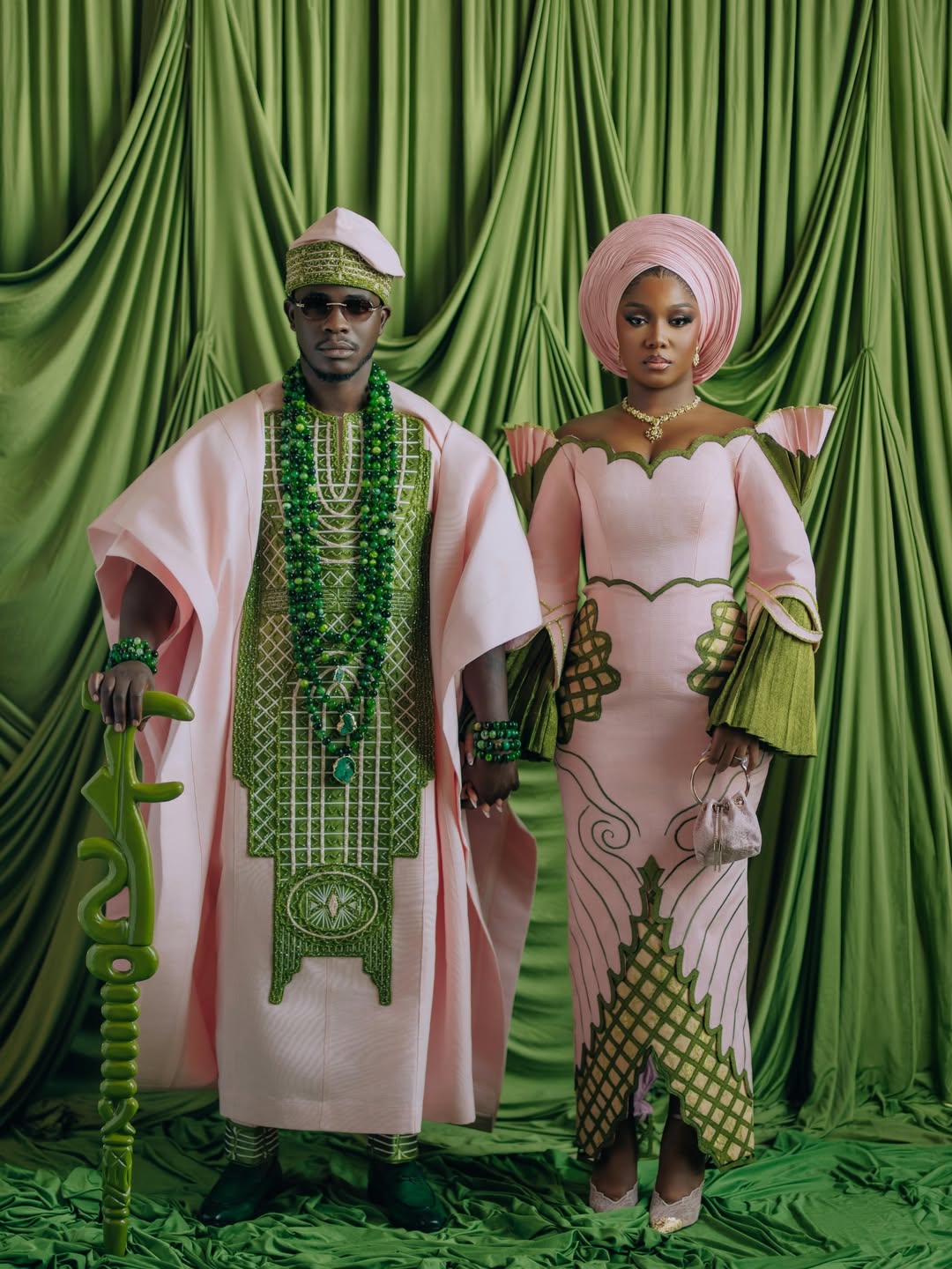 Simi Sanya and Femi Dapson posing for their first look at their traditional wedding in blush pink and forest green outfits.