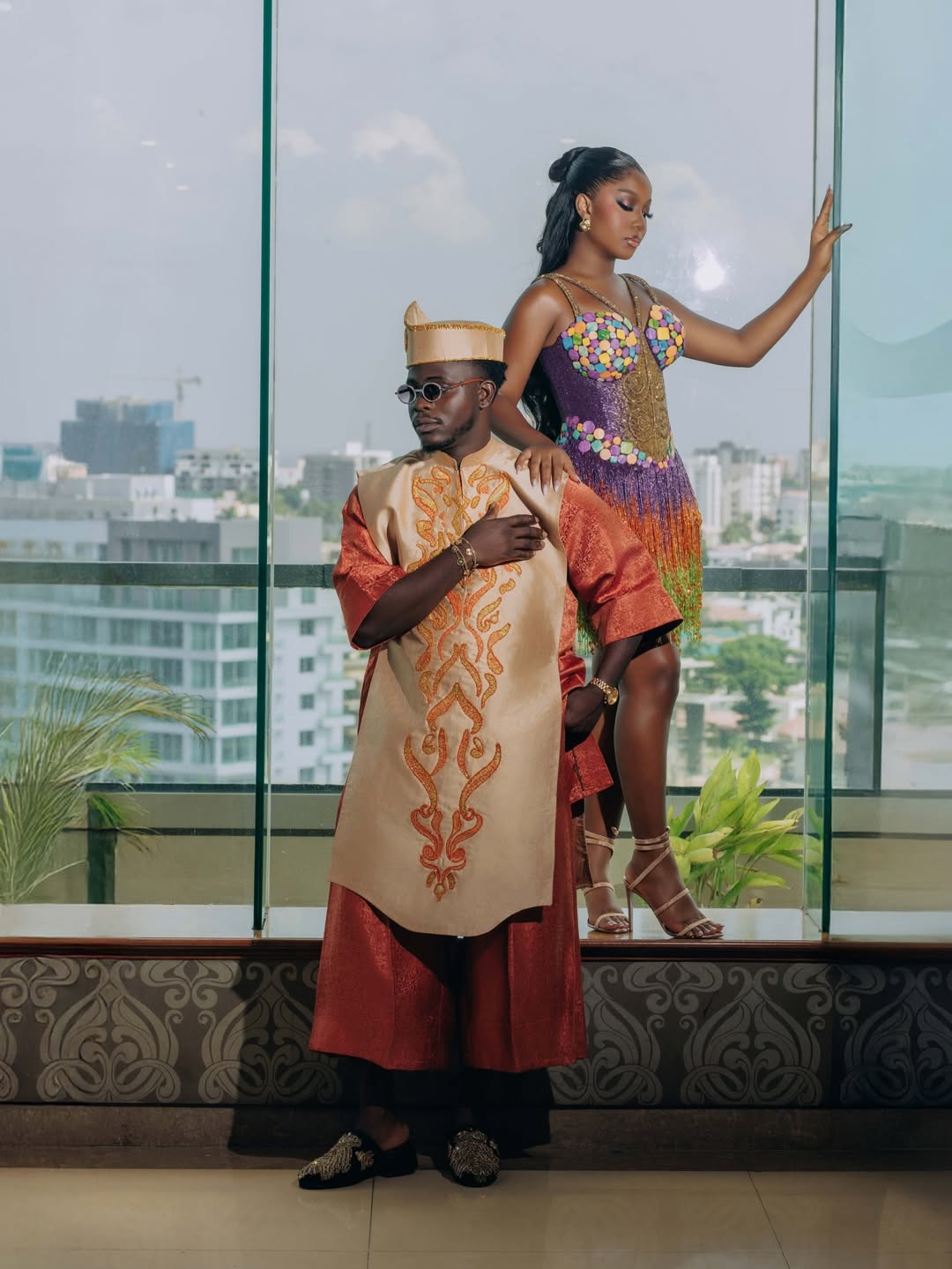 Simi Sanya in a purple fringe mini dress with multi-coloured disc appliqués and Femi Dapson in a burnt-orange brocade set with a gold-embroidered cream vest at their traditional wedding after-party.