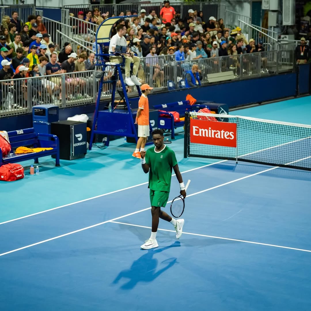 Moïse Kouame celebrates his first ATP Tour win at the 2026 Miami Open, walking past court-side branding after defeating Zachary Svajda.