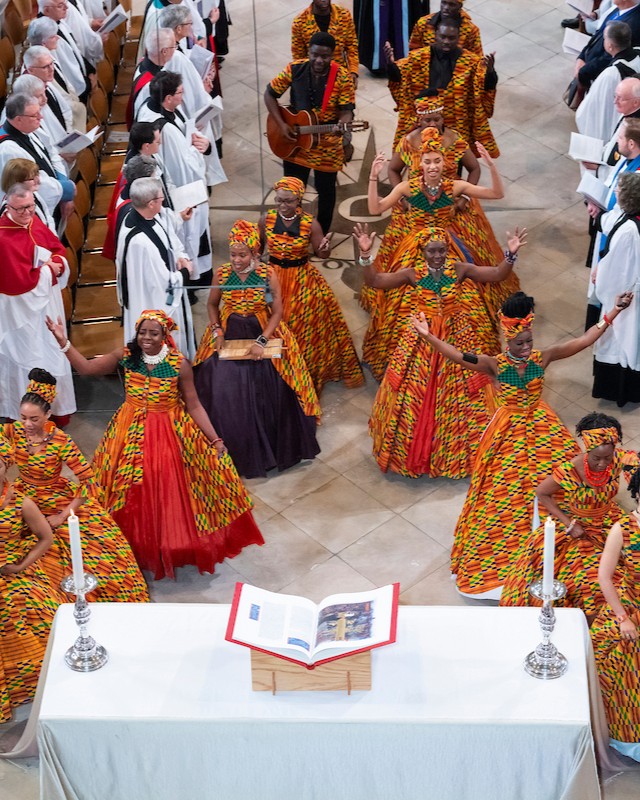 An African choir dressed in vibrant Kente-patterned attire performing during Dame Sarah Mullally's installation at Canterbury Cathedral.