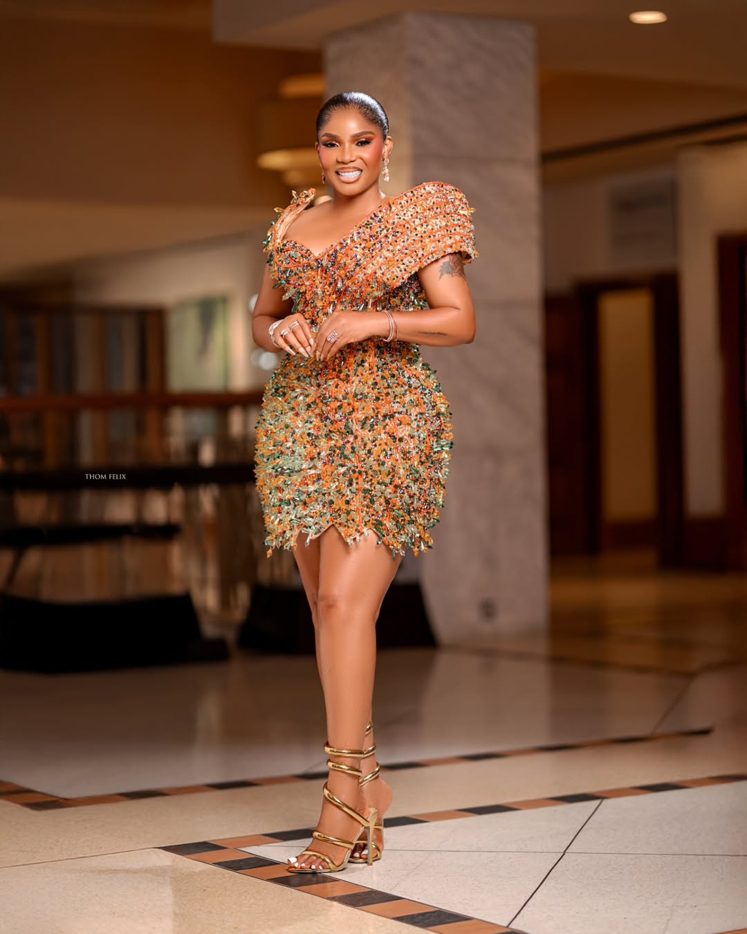 Iyabo Ojo at The Return of Arinzo premiere wearing a burnt orange and forest green mini dress covered in layered crystal fringing.