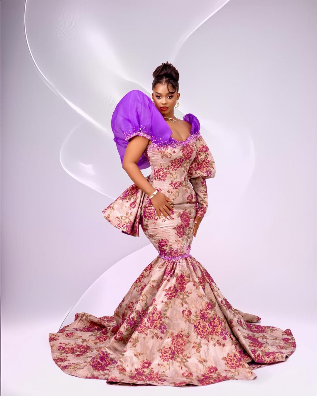 Priscilla Ojo in a purple floral brocade gown with exaggerated violet organza puffed sleeves.