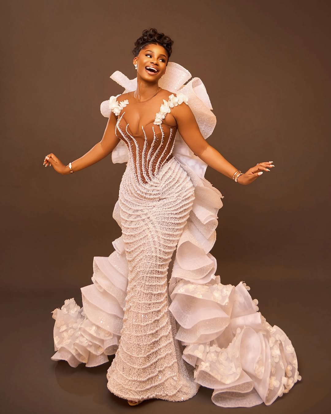 Priscilla Ojo in a white beaded mermaid gown with 3D floral appliqués and a ruffled petal train.