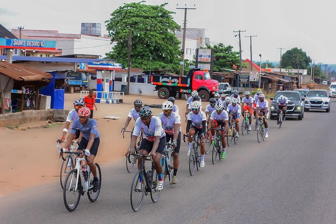 Kanye Tagbo-Okeke in a grey cycling jersey leading a pack of cyclists on a highway in Benin during his Enugu to Lagos record-breaking ride.