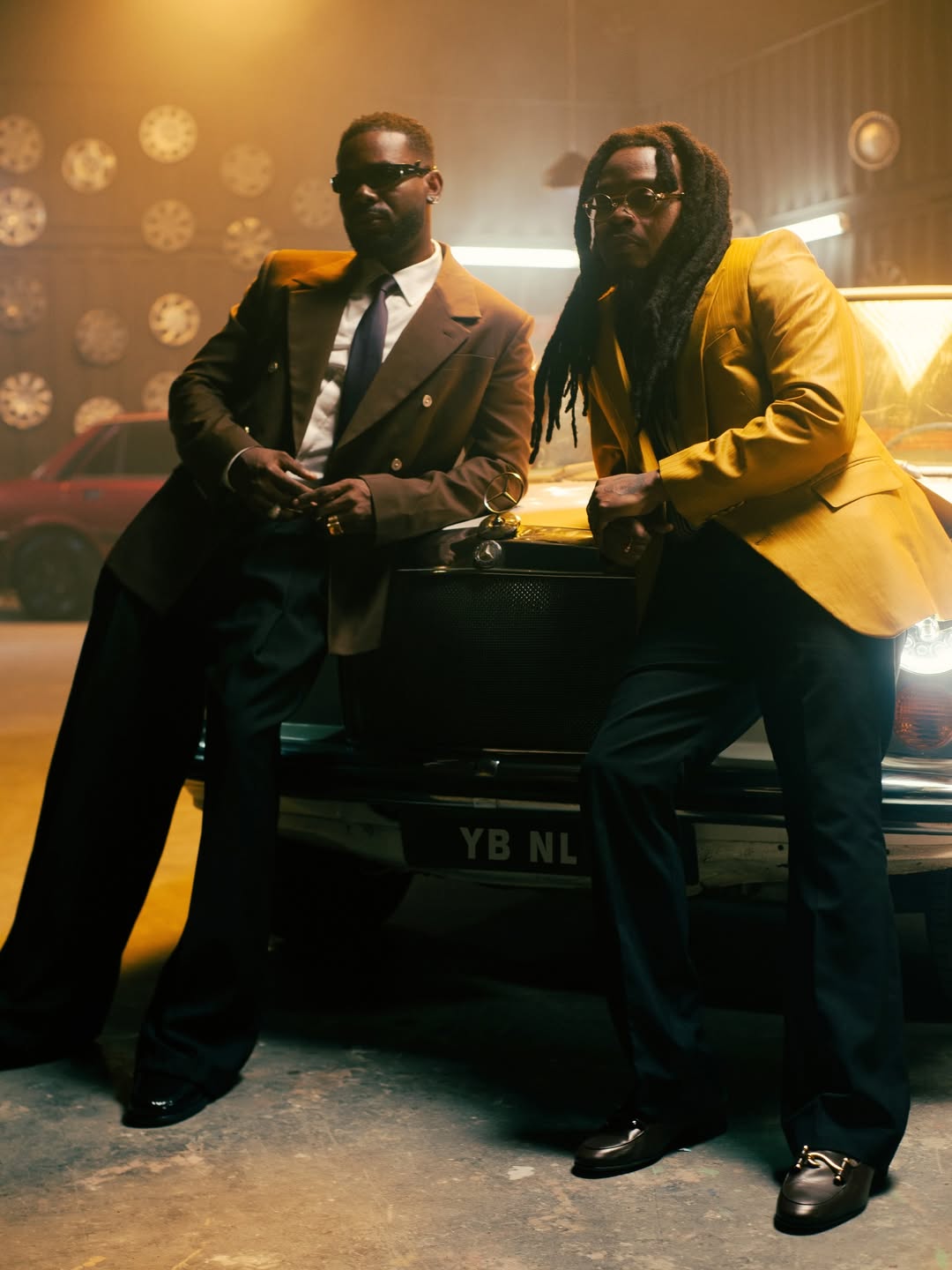 Adekunle Gold and Olamide posing in a retro garage with a vintage Mercedes-Benz for their 2026 collaboration 'Formation.'