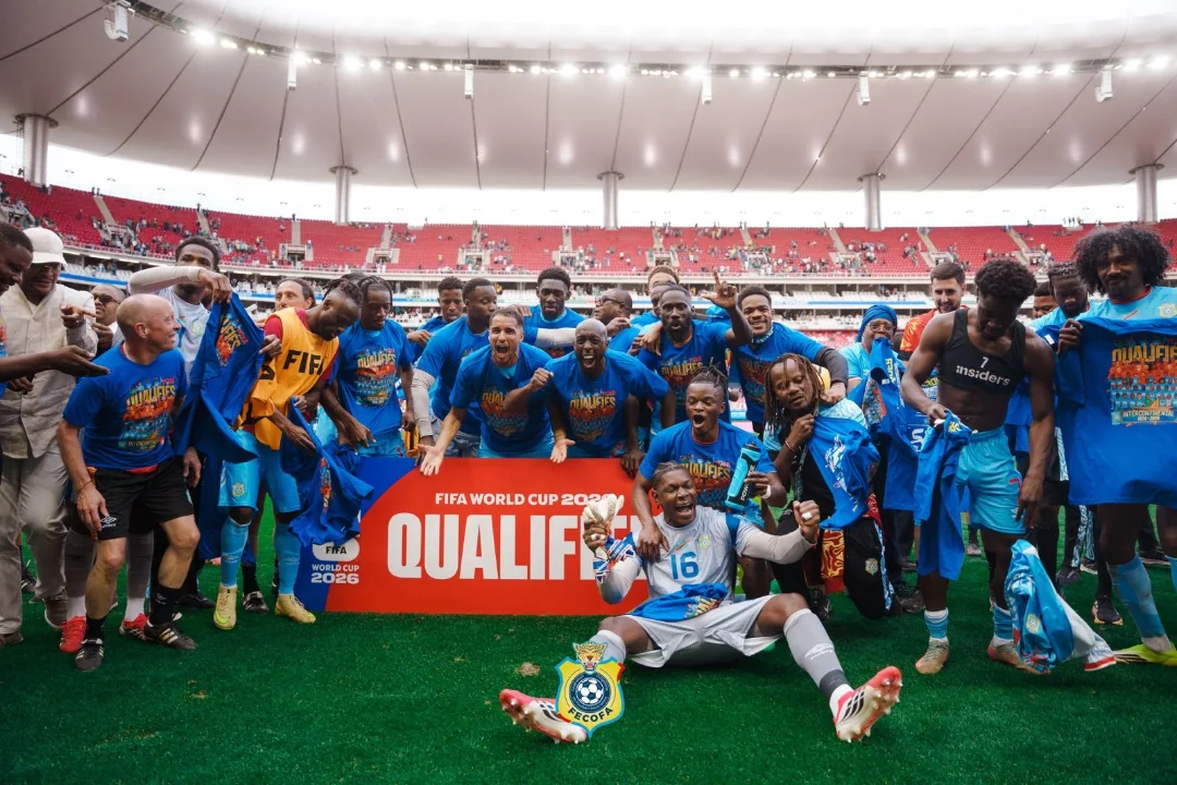 DR Congo national football team celebrating 2026 World Cup qualification on pitch with "QUALIFIED" banner.