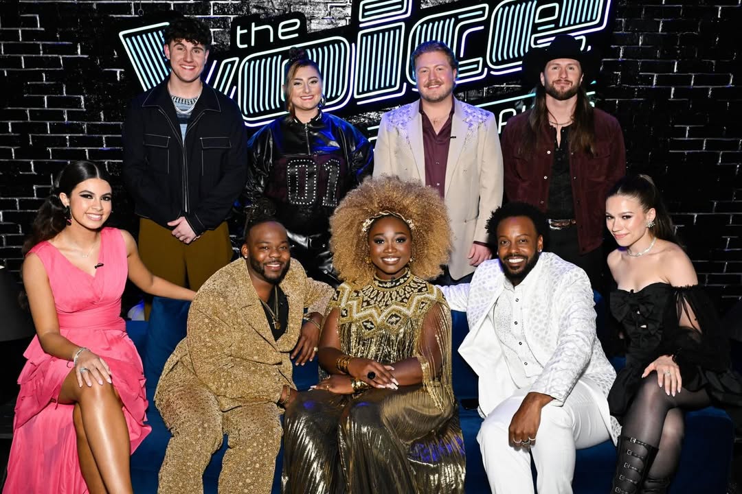 The top nine finalists of The Voice Season 29 sitting together on a blue velvet sofa, with winner Alexia Jayy in a gold fringed dress at the centre.