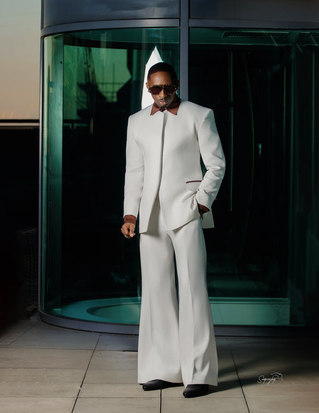 Juma Jux wearing an all-white mandarin-collar suit by Swazzi with burgundy piping and flared trousers.