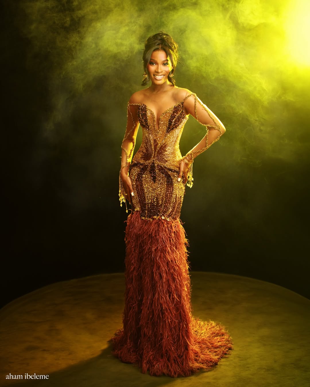 Jemima Osunde in a floor-length gold and bronze beaded sequin gown with a burnt-orange feathery train by DashyBrins, photographed by Aham Ibeleme under golden atmospheric lighting for her 30th birthday shoot