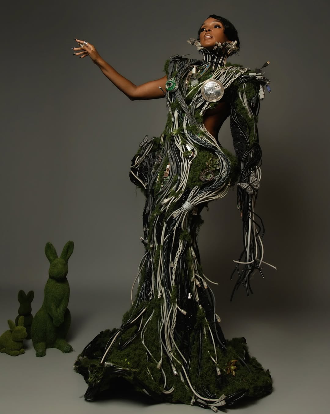 Janelle Monáe interprets "Fashion Is Art" in a Christian Siriano creation built from 230 electrical wires, Ethernet cables, and server wires. The "techno-organic" look incorporates live moss, succulents, 5,000 black crystals, and moving mechanical butterflies on a motherboard bodice.