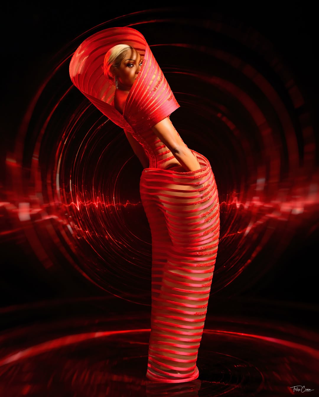 Editorial shot of Osas Ighodaro with her face partially framed by a sculptural red collar.