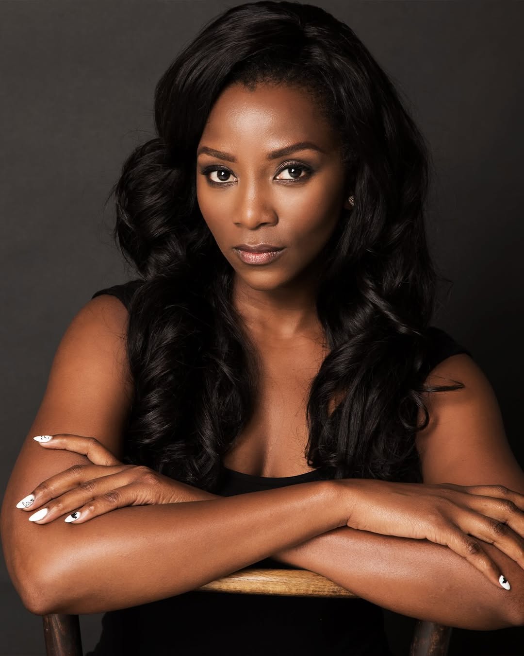 A portrait of Nigerian actress Genevieve Nnaji with long wavy hair and white manicured nails, confirmed as part of the BBC Wahala cast.