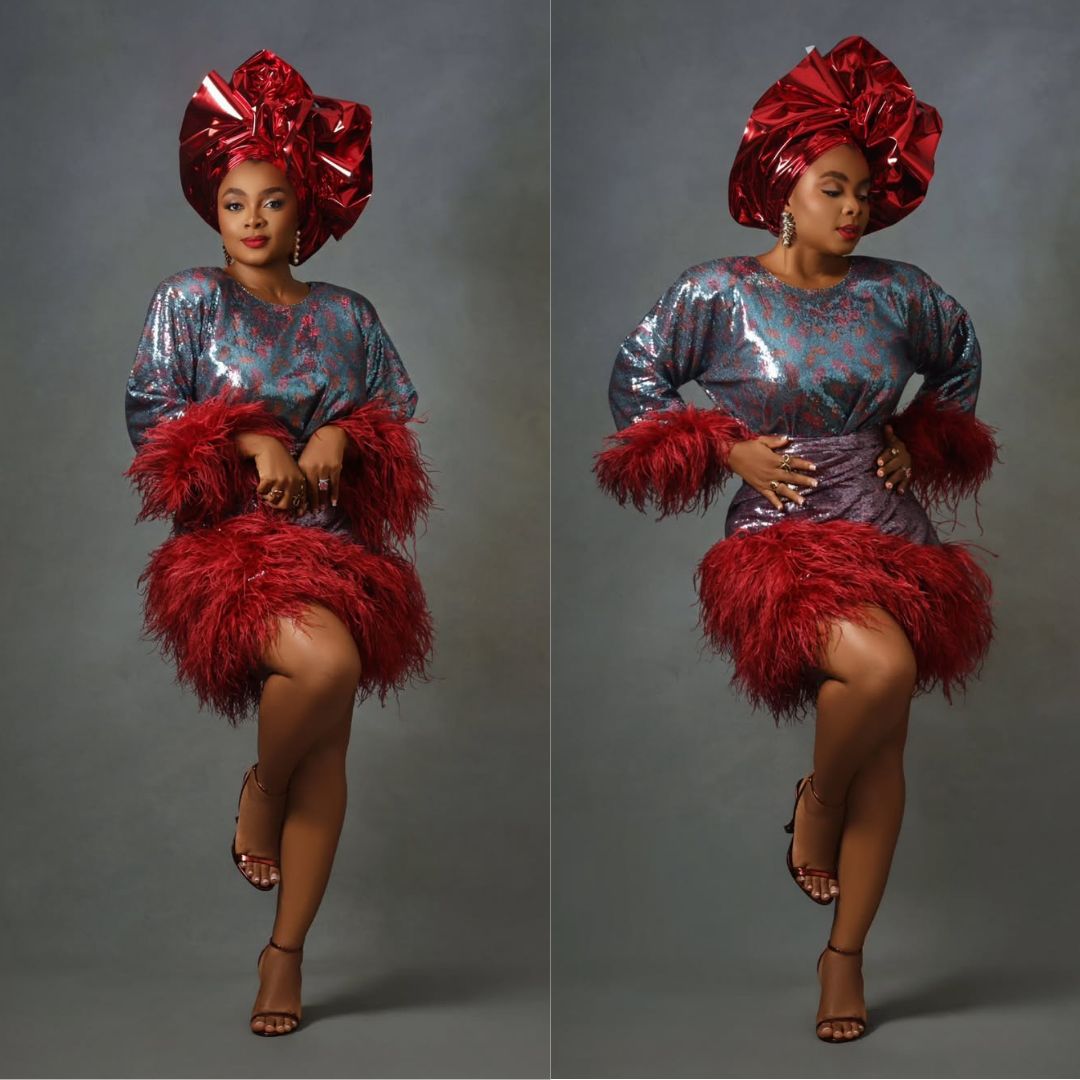Actress Bimbo Akintola in a shimmering blue and pink sequinned Oleku by Wanni Fuga featuring dense crimson feather trims along the sleeves and hemline.