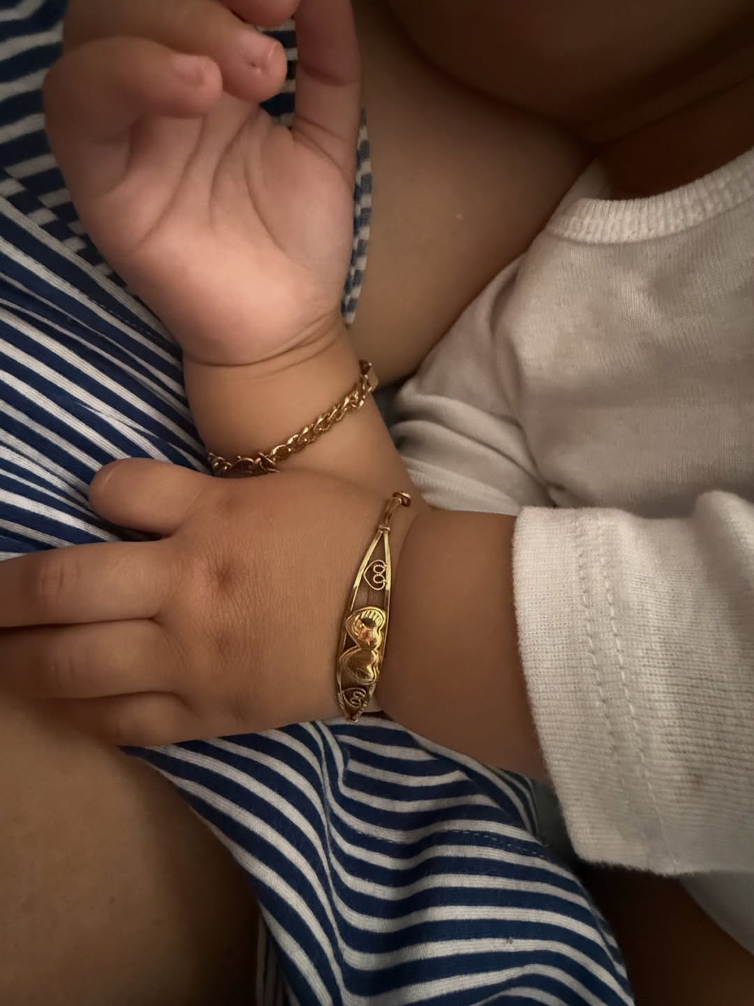 Close-up of Nollywood actress Adunni Ade's young daughter wearing gold chain bracelets over a white long-sleeved shirt.