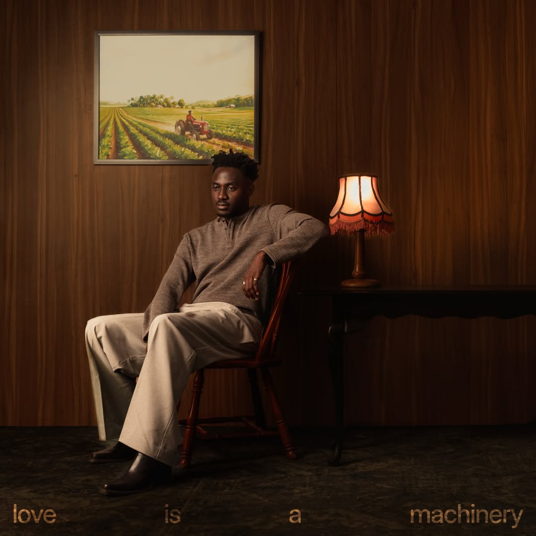 Official album artwork cover for Anendlessocean's Love Is A Machinery featuring the artist sitting on a wooden chair in a wood-panelled room.