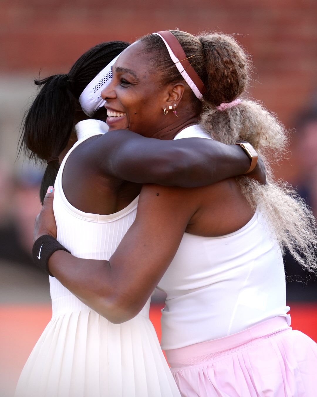Serena Williams smiling warmly while embracing her doubles partner Victoria Mboko following their straight-sets victory.
