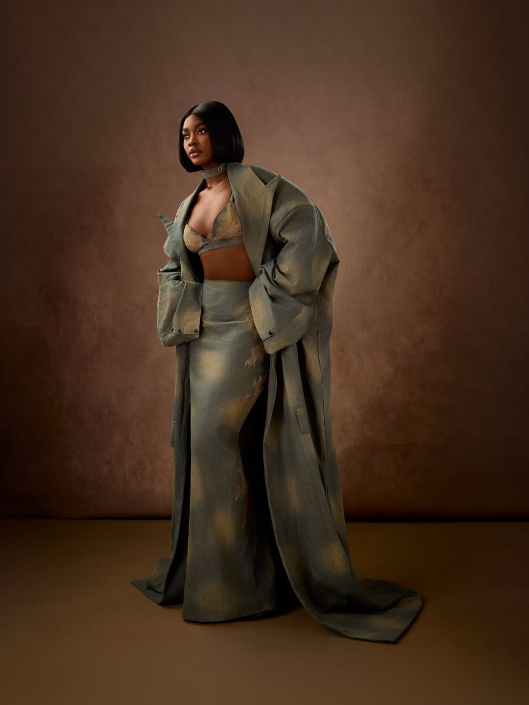 Dede Ashiogwu wrapping a voluminous custom denim trench coat around her silhouette at the BBNaija Season 10 reunion.