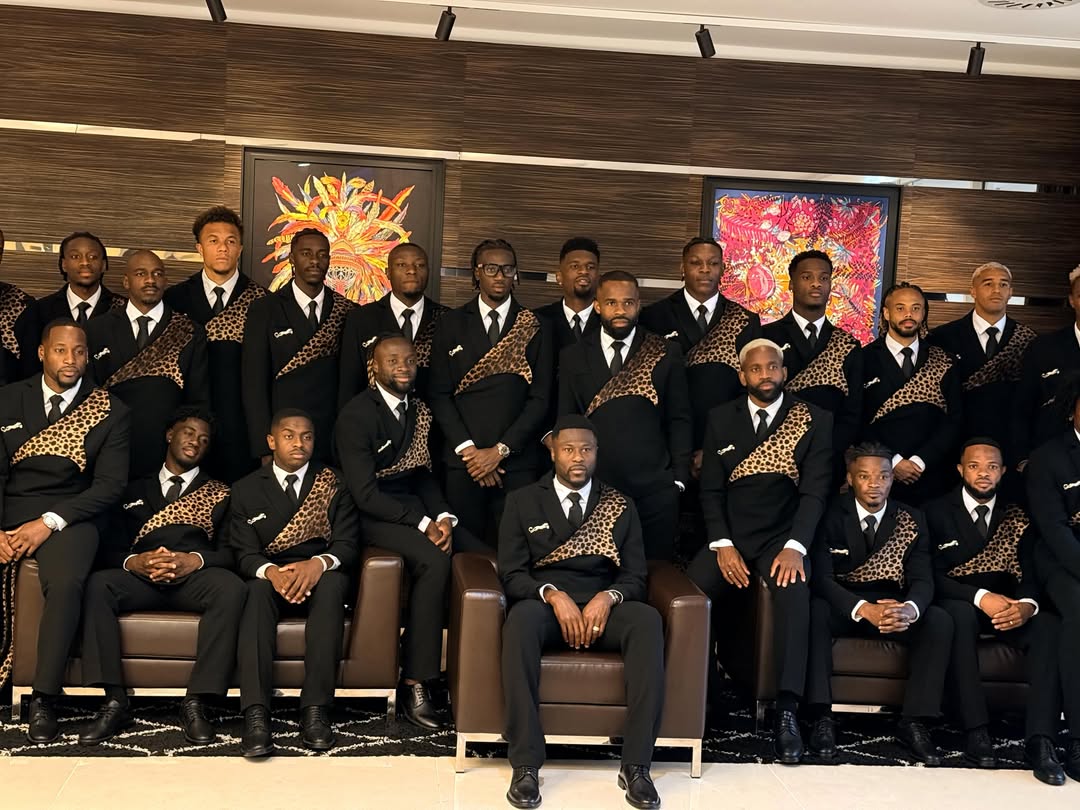 DR Congo football players and staff posing indoors on leather sofas in their leopard-print theme formal wear.