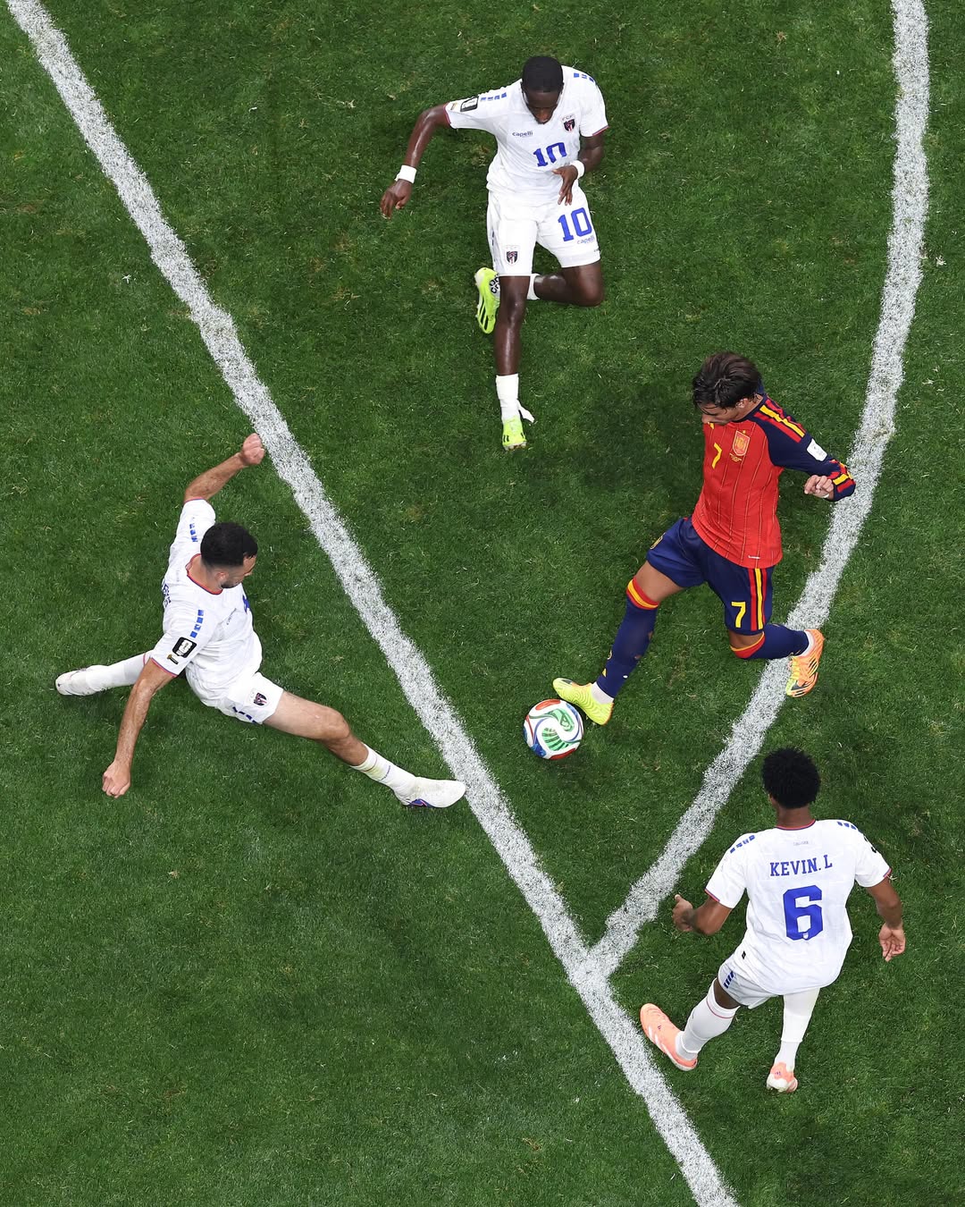 Spanish player jersey number 7 controlling the ball while surrounded by three Cabo Verde defenders on the pitch.