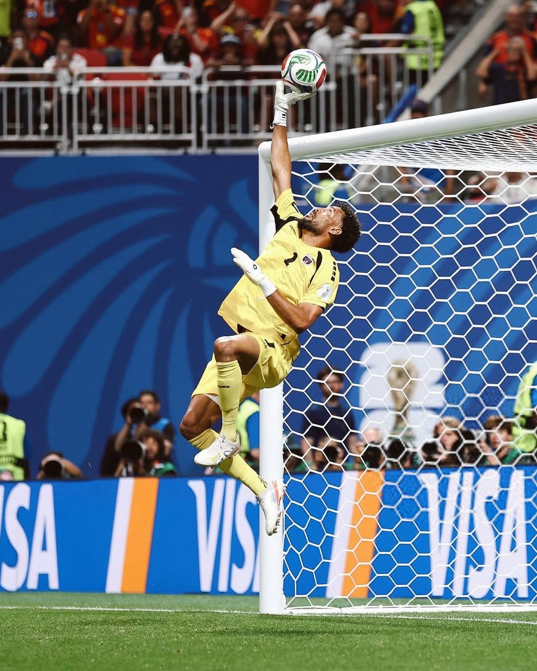 Cabo Verde goalkeeper Vozinha in a yellow jersey leaping high in the air to tip the football over the crossbar.