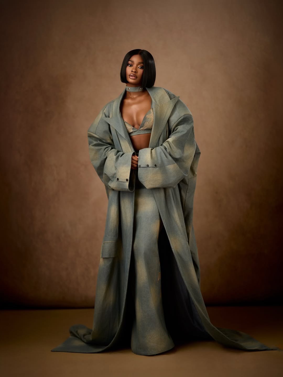 Dede Ashiogwu wrapping a voluminous custom denim trench coat around her silhouette at the BBNaija Season 10 reunion.