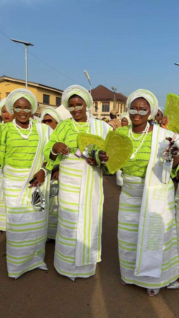 A group of women dancing together at the Ojude Oba Festival wearing uniform lime green and white striped buba and iro.