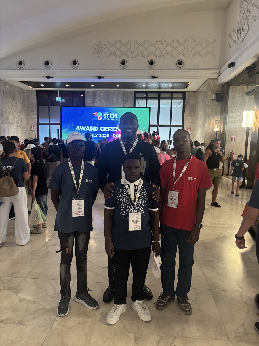 Alex Onyia standing with gold medalists Don Anele Munachimso, Egejurum Onyedikachi Ethan, and Chimdiebube Onwubiko at the award ceremony hall.