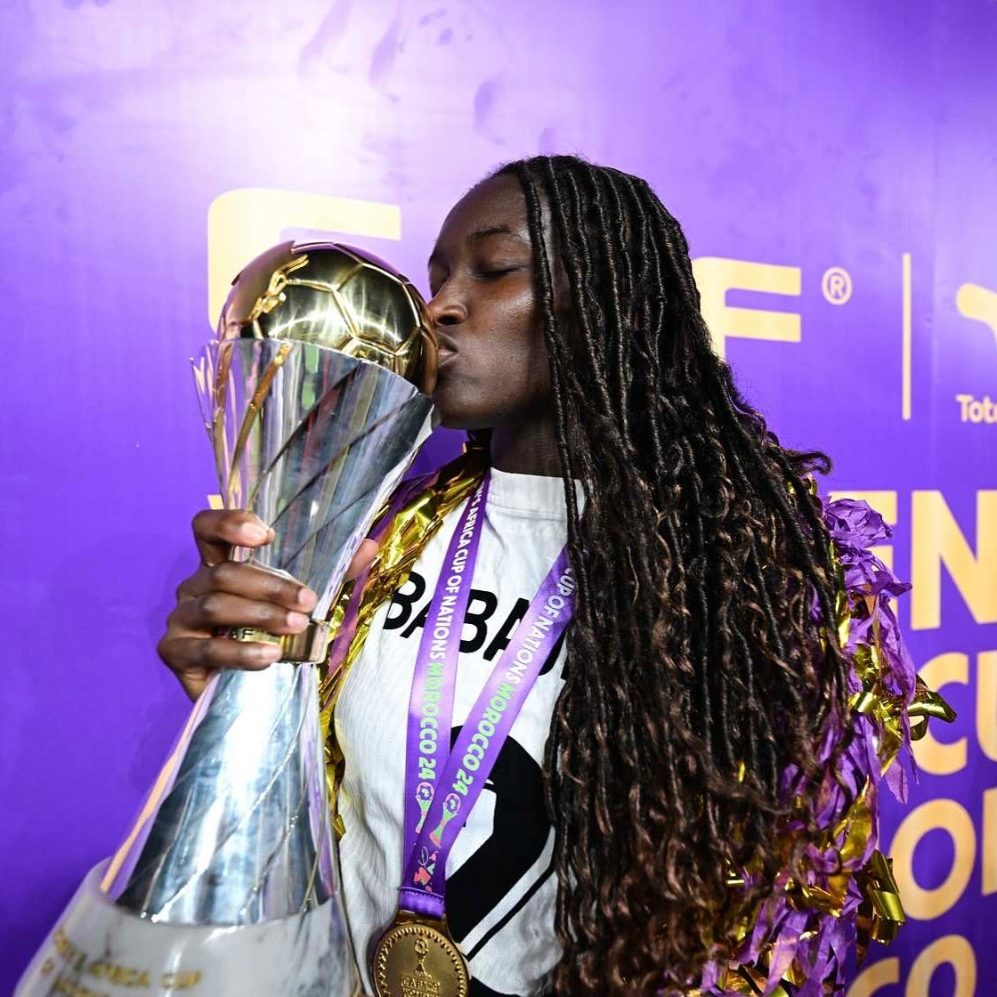Nigeria winger and forward Omorinsola Babajide kissing the official TotalEnergies CAF Women's Africa Cup of Nations trophy while wearing her gold medal after the 2024 final victory.