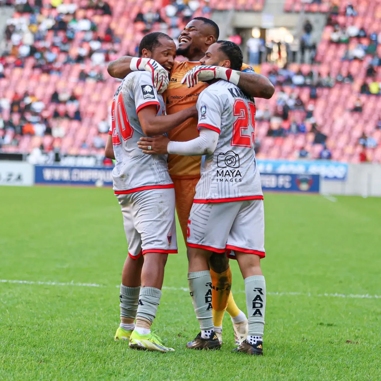 Chippa United goalkeeper Stanley Nwabali smiling and embracing teammates on the pitch during a Betway Premiership match.