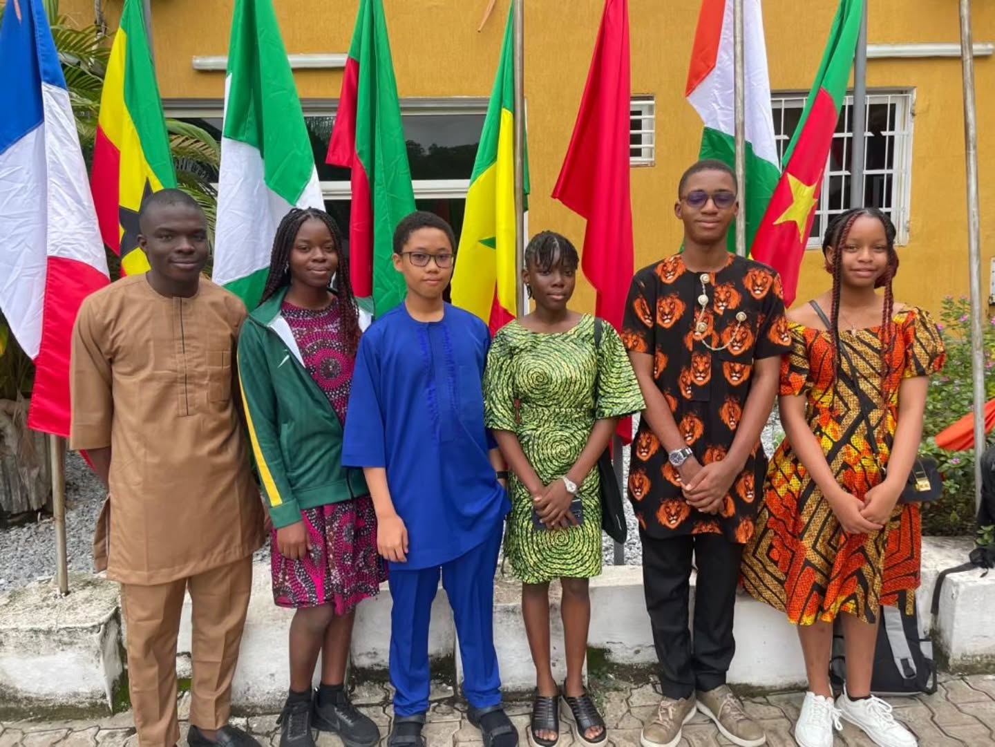 Six Team Nigeria secondary school student representatives dressed in traditional African attire standing in front of continental flags at the Pan-African Mathematics Olympiad in Yamoussoukro Ivory Coast.