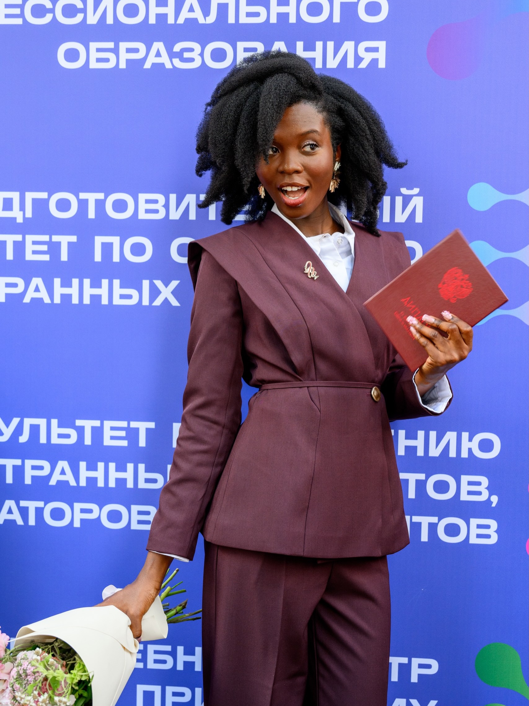 Dr Dorcas Akanbi holds her medical degree diploma and a flower bouquet at her graduation in Russia.