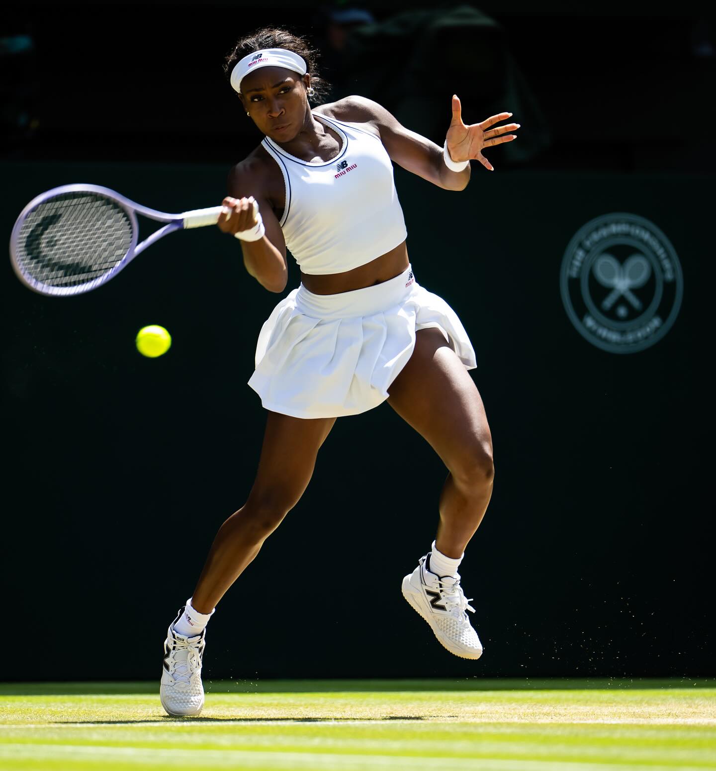 Coco Gauff striking a powerful running forehand on the grass court during the Wimbledon quarter-finals.