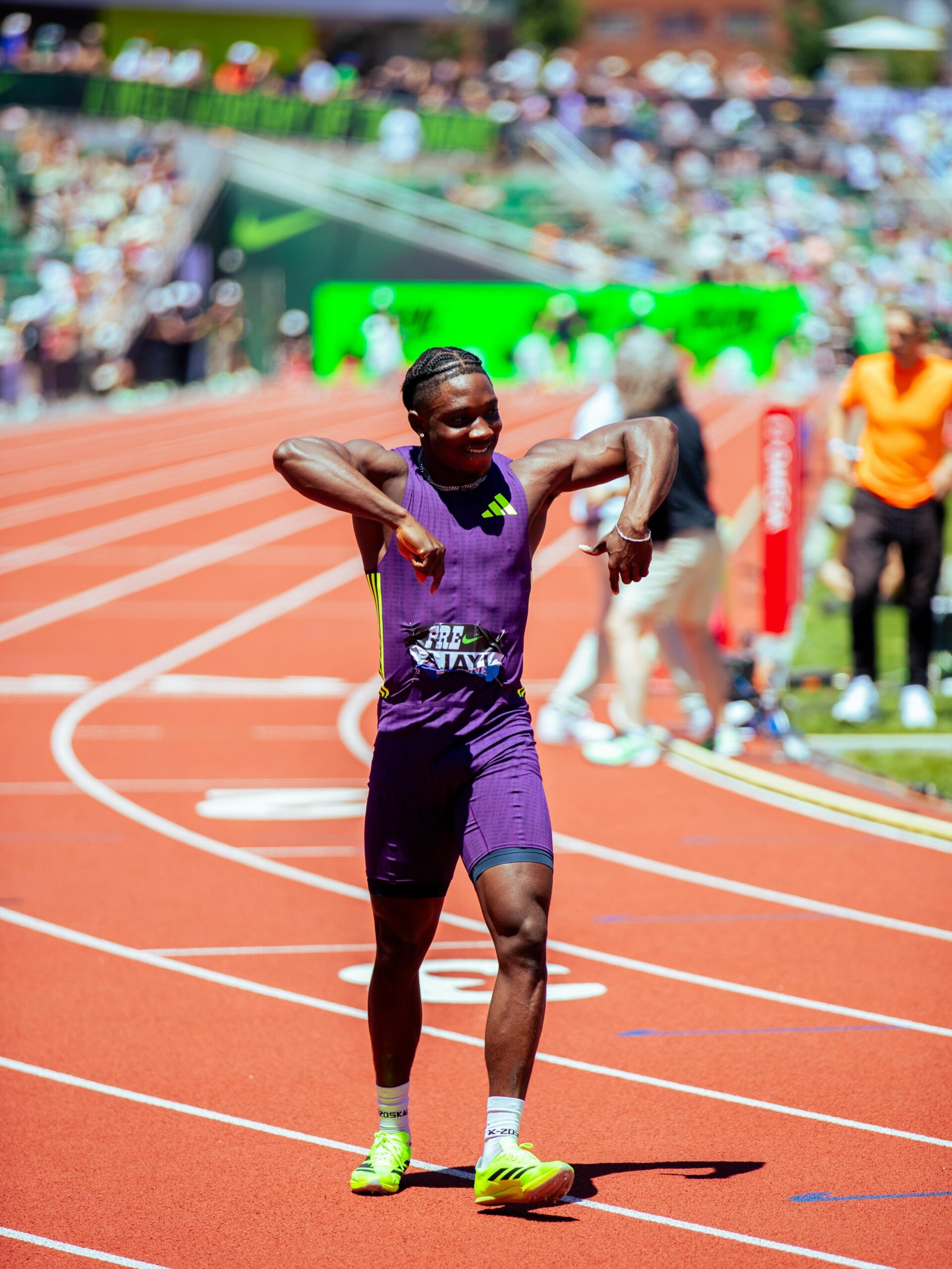 Nigerian sprinter Kanyinsola Ajayi smiling and flexing his arms in celebration on the running track at Hayward Field.