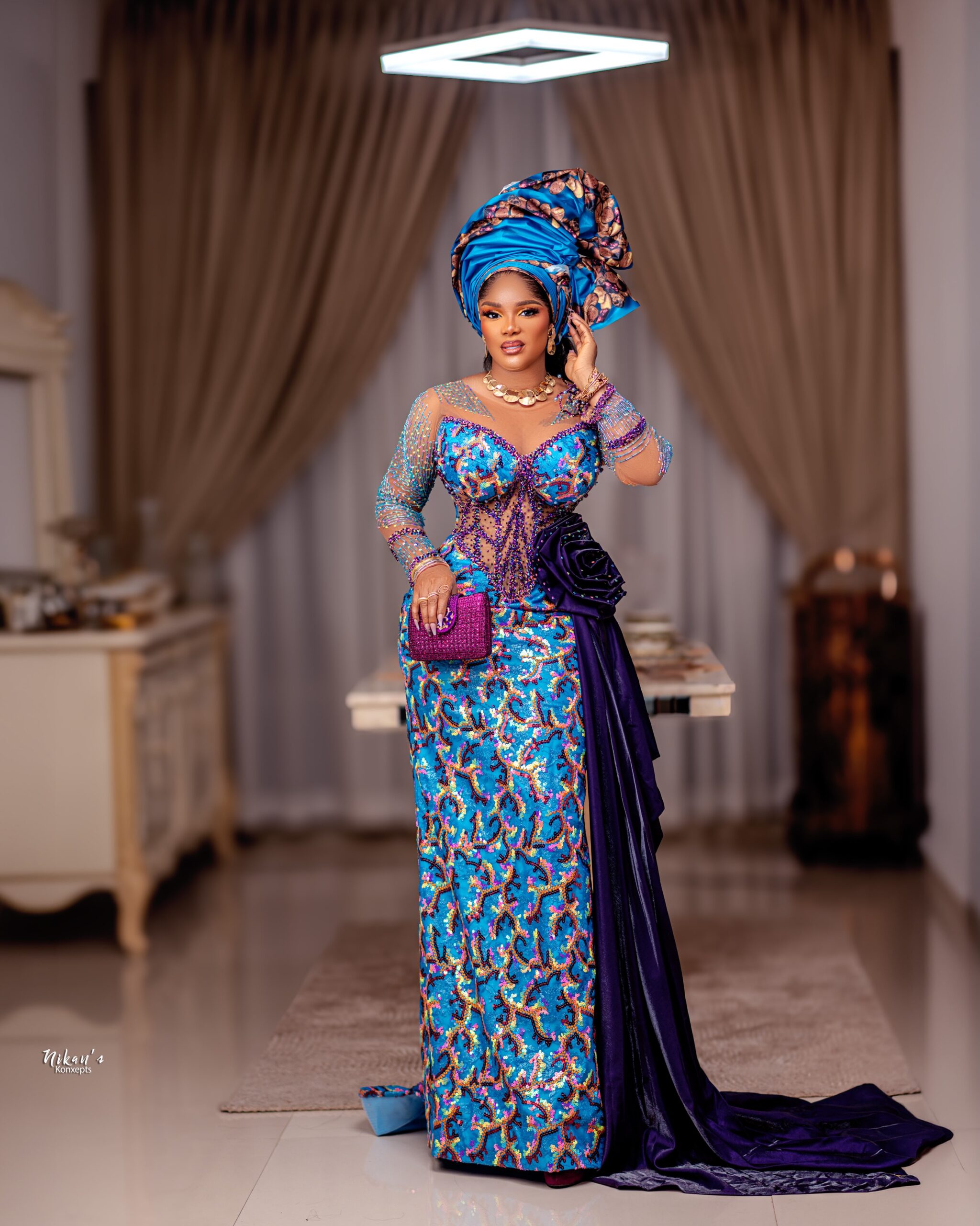Iyabo Ojo wearing the complete turquoise and purple Aso Ebi ensemble, holding a purple structured clutch bag.