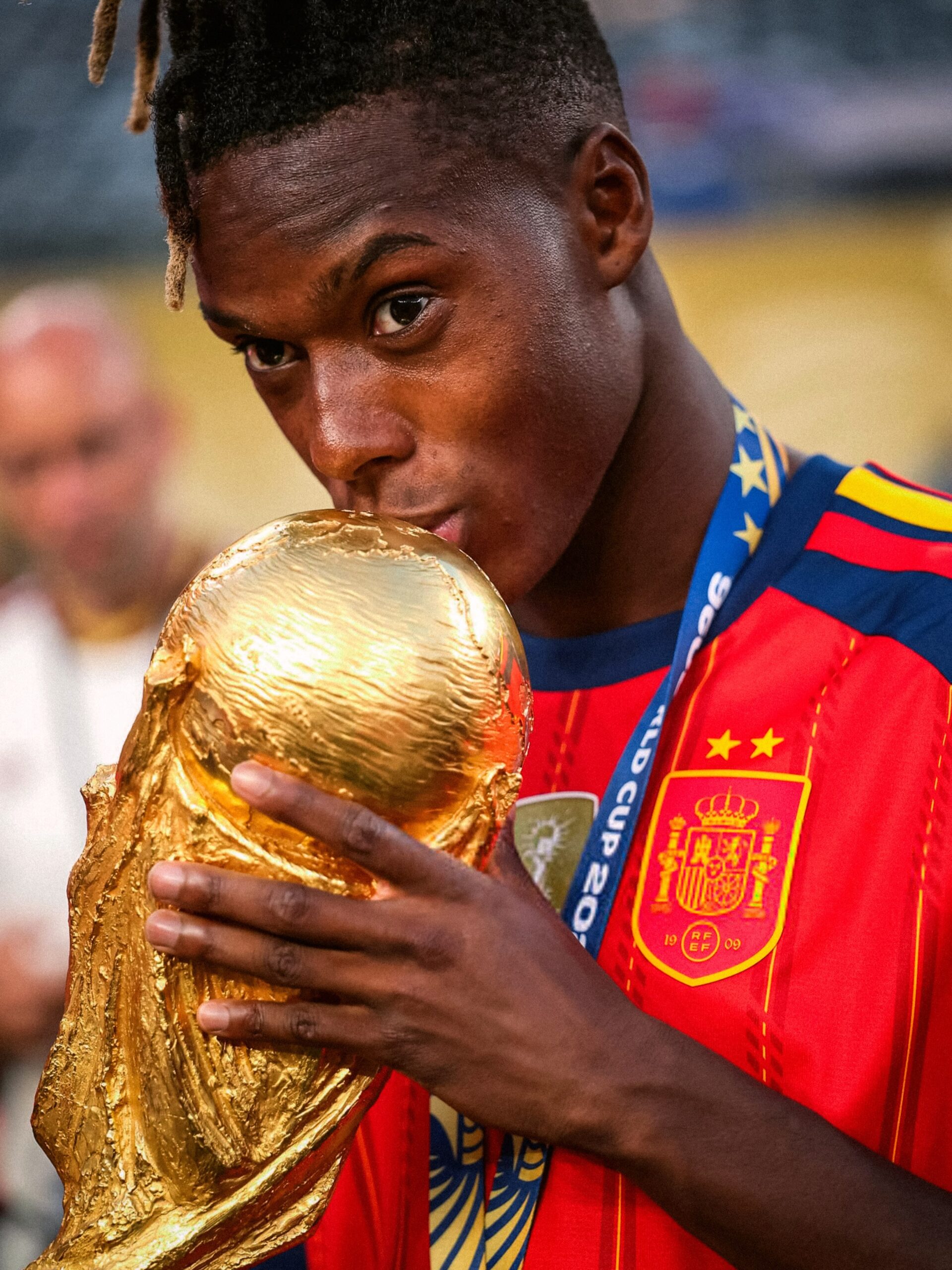 Nico Williams presses his lips against the gold FIFA World Cup trophy wearing his Spain national shirt and winner medal.
