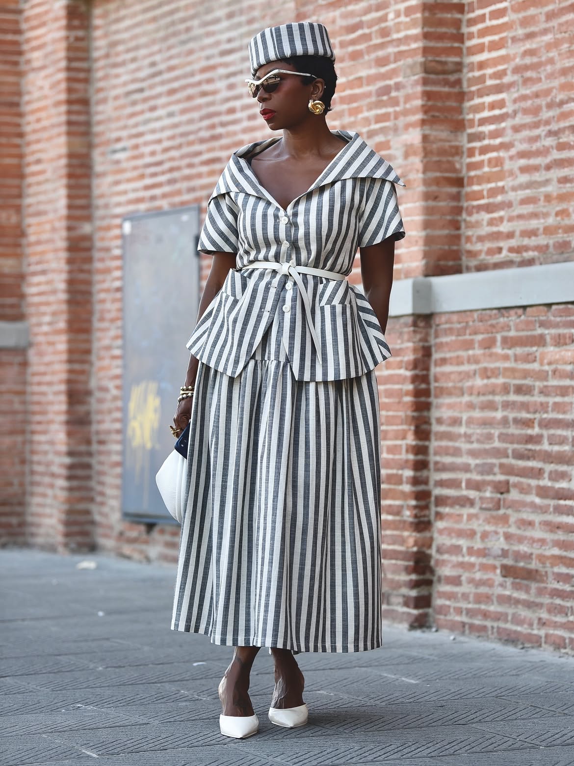 black woman wearing matching skirt set with pill box hat