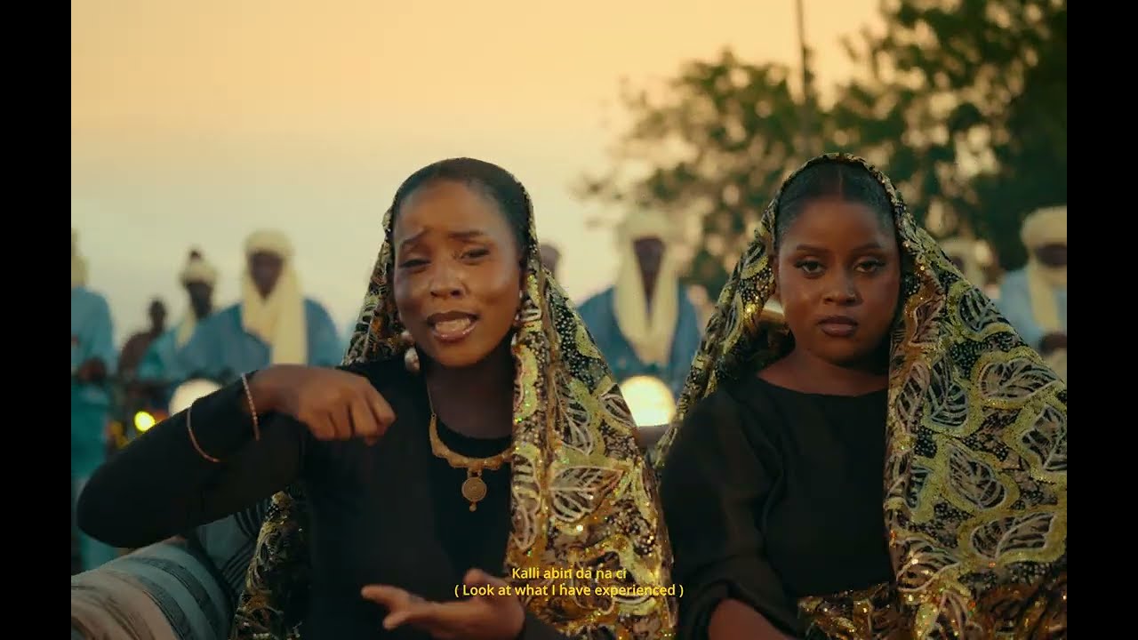 Musical duo Oiza x Meyi wearing gold-embroidered Northern veils and traditional black attire while singing in the official Na Je music video by Falz.