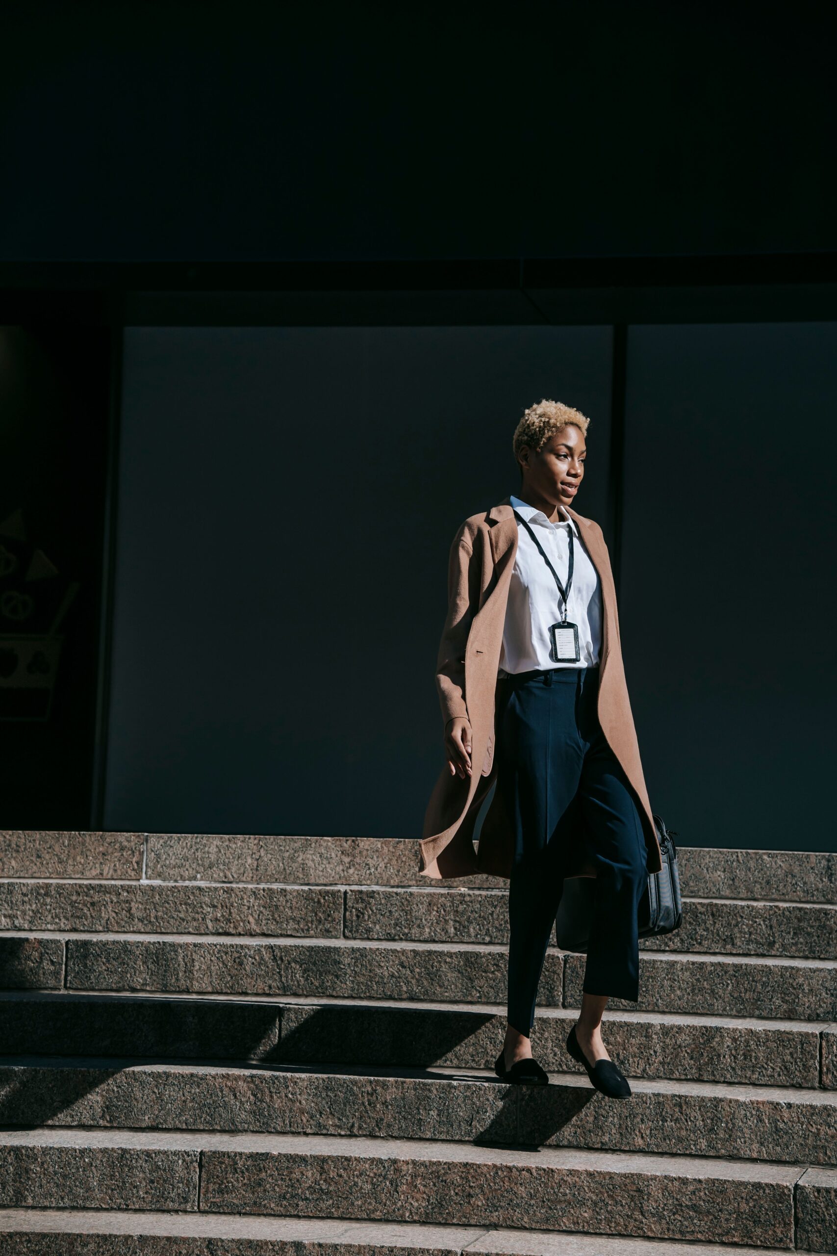 A confident stylish woman descends city stairs, embodying elegance and modern business fashion
